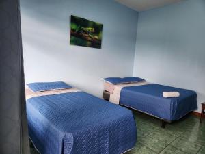 2 camas en una habitación con sábanas azules en Hotel y Restaurante El Marino, en Santa Cruz