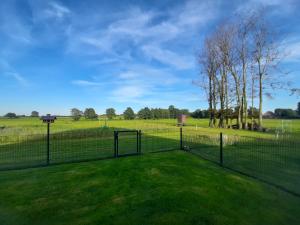 Ein Zaun mitten auf einem Grasfeld in der Unterkunft Ferienhaus Groß Moorburg in Südbrookmerland