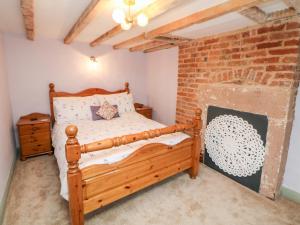 a bedroom with a wooden bed and a brick wall at Elsie's Escape in Matlock