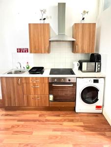 La cuisine est équipée d'un évier, d'une cuisinière et d'un lave-vaisselle. dans l'établissement Aldgate Rooms, à Londres