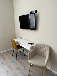 escritorio blanco con silla y TV en la pared en H30 Apartman, en Pécs