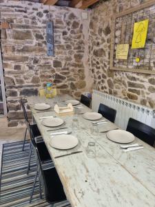 a large wooden table with chairs and a stone wall at Albergue Gabino in El Ganso