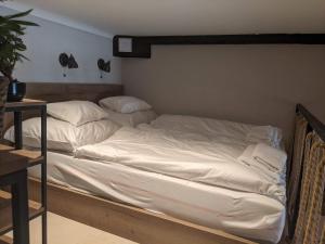 ein Bett mit weißer Bettwäsche und Kissen darauf in der Unterkunft Ó 38 Luxe Loft in Budapest