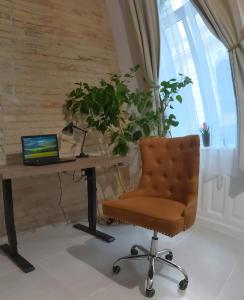 uma secretária com um computador portátil e uma cadeira ao lado de uma janela em Ó 38 Luxe Loft em Budapeste