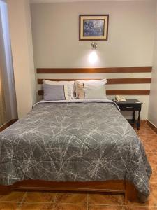 a bedroom with a bed with a gray comforter at Hotel Begonias in Lambayeque