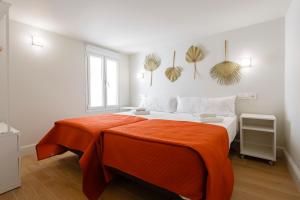 a bedroom with a large bed with an orange blanket at Casa Manuel de Falla by Cadiz4Rentals in Cádiz