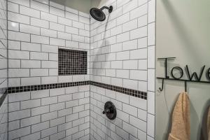 a white tiled shower with a black and white at Lazy Fox Hideout in Sevierville