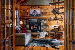 a living room with a stone fireplace in a log cabin at Lazy Fox Hideout in Sevierville