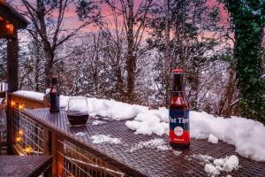 a bottle of wine and a glass on a deck with snow at Lazy Fox Hideout in Sevierville