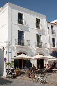 ein weißes Gebäude mit Tischen und Sonnenschirmen davor in der Unterkunft Can Set in Cadaqués