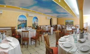 a dining room with white tables and chairs and a mural at Hotel Ristorante "Da Valerio" in Cittaducale