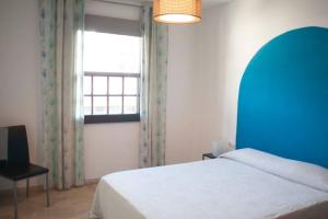 een slaapkamer met een bed met een blauw hoofdeinde en een raam bij Localización inmejorable con garaje incluido in Puerto de la Cruz