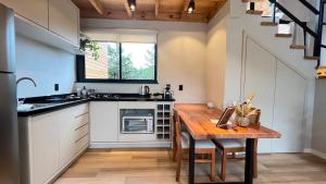 uma cozinha com uma mesa de madeira e uma bancada em Cabanas Jardim de Tereza em São Joaquim