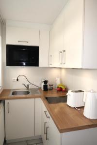 a kitchen with white cabinets and a sink and a microwave at Julia's Mosel Villa Appartement NICOLAS in Traben-Trarbach