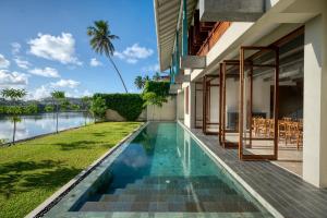 a swimming pool next to a house with a view of the water at Sitara Weligama in Weligama
