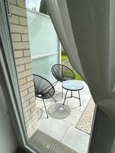 eine Terrasse mit 2 Stühlen, einem Tisch und einem Fenster in der Unterkunft Paris to Bochum, 4 Pers. Apartm. in Bochum