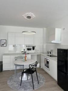 eine weiße Küche mit einem Tisch und einem Stuhl darin in der Unterkunft Paris to Bochum, 4 Pers. Apartm. in Bochum