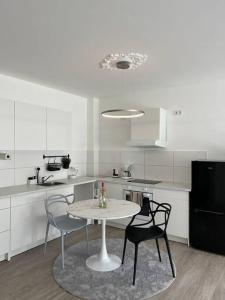 eine weiße Küche mit einem Tisch und Stühlen in der Unterkunft Paris to Bochum, 4 Pers. Apartm. in Bochum