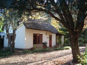 a small white house with a thatch roof at Peebles Cottage in Clarens