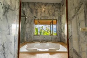 un bagno con vasca e finestra di 悬崖别墅 无边海景 直达海滩 五卧泰式独栋私人泳池别墅 超漂亮日出 a Phuket