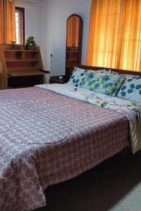 a bedroom with a large bed with a pink comforter at NEST Mdy in Mananthavady