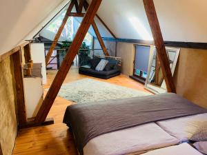 Cette chambre mansardée comprend un lit et un canapé. dans l'établissement Loftwohnung in einer preisgekrönten Denkmalhofreite, à Groß-Umstadt
