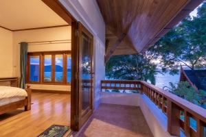 a bedroom with a balcony with a view of the water at 悬崖别墅 无边海景 直达海滩 五卧泰式独栋私人泳池别墅 超漂亮日出 in Phuket Town