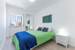 a white bedroom with a green bed and a window at Vieira Azul in Armação de Pêra