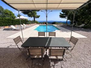 a table with chairs and an umbrella next to a pool at Villa "Le Sortilège" vue panoramique et piscine in Tourtour