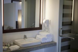 a bathroom with a sink and a mirror and towels at The Calm Resort & Spa in Pasikuda