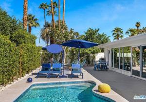 een zwembad met stoelen en parasols naast een huis bij wonderfully reimagined 3bd 2bath mid-century palm springs home in Palm Springs