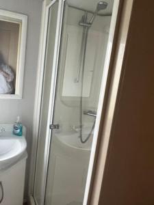 a shower in a bathroom with a glass door at Lisa and Laddy Caravan Hire in Meliden