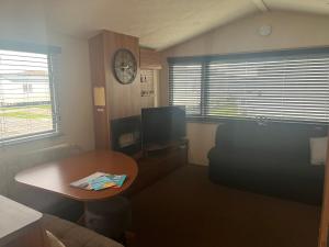 a small living room with a table and a tv at Lisa and Laddy Caravan Hire in Meliden