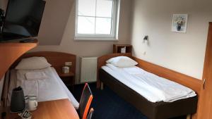 a room with two beds and a table and a tv at Noclegi Agape in Szczecin-Płonia