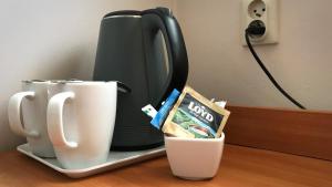 a coffee maker and cups on a table at Noclegi Agape in Szczecin-Płonia