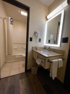 a bathroom with a sink and a shower and a mirror at Days Inn & Suites by Wyndham Kaukauna WI in Kaukauna