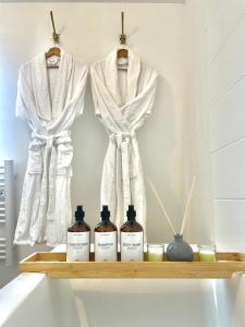 a shelf with three bottles of soap and towels at LIVABLŌM "Maison et Parking Privée" 
