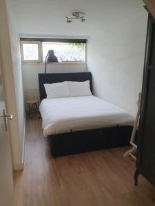 a bed in a small room with a window at 't Hoekhuisje in Katwijk aan Zee