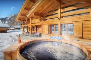 a wooden house with a hot tub in the snow at Chalet Tolar - OVO Network in Le Grand-Bornand