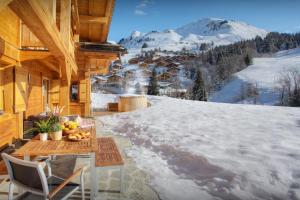 a table and chairs on a balcony with a mountain at Chalet Tolar - OVO Network in Le Grand-Bornand