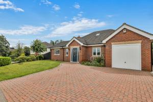 a brick house with a white garage on a brick driveway at Silver Stag Properties, 3 BR Dormer Bungalow in Thringstone