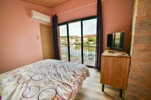 1 dormitorio con cama, TV y balcón en Maison Bord de l'eau, en Ornans