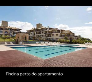 uma piscina em frente a alguns edifícios de apartamentos em Apartamento Dentro Resort Costao do Santinho NOT ALL INCLUSIVE em Florianópolis