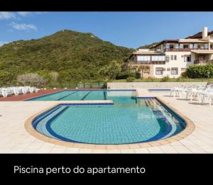 a large swimming pool with a mountain in the background at Apartamento Dentro Resort Costao do Santinho NOT ALL INCLUSIVE in Florianópolis