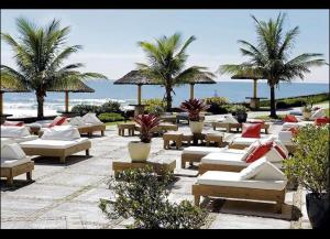 フロリアノポリスにあるApartamento Dentro Resort Costao do Santinho NOT ALL INCLUSIVEの浜辺のヤシの木とラウンジチェアの列