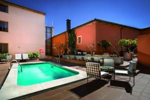 a swimming pool in a courtyard with chairs and a building at Izan Trujillo in Trujillo