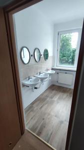 a bathroom with two sinks and mirrors and a window at Pokoje 24h ul. Bagrowa Kraków in Krakow