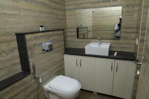 La salle de bains est pourvue de toilettes, d'un lavabo et d'un miroir. dans l'établissement SENTHUR INN VELLORE Sathuvachari, à Vellore