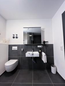 W łazience znajduje się umywalka, toaleta i lustro. w obiekcie Luxusferienwohnung mit Sauna - NEUBAU w mieście Ofterschwang