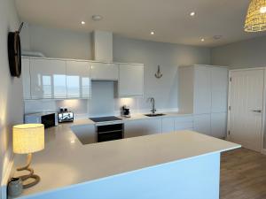 a kitchen with white cabinets and a white counter top at Ocean View Suite - Near Hythe - On Beach Seafront - Private Parking in Dymchurch